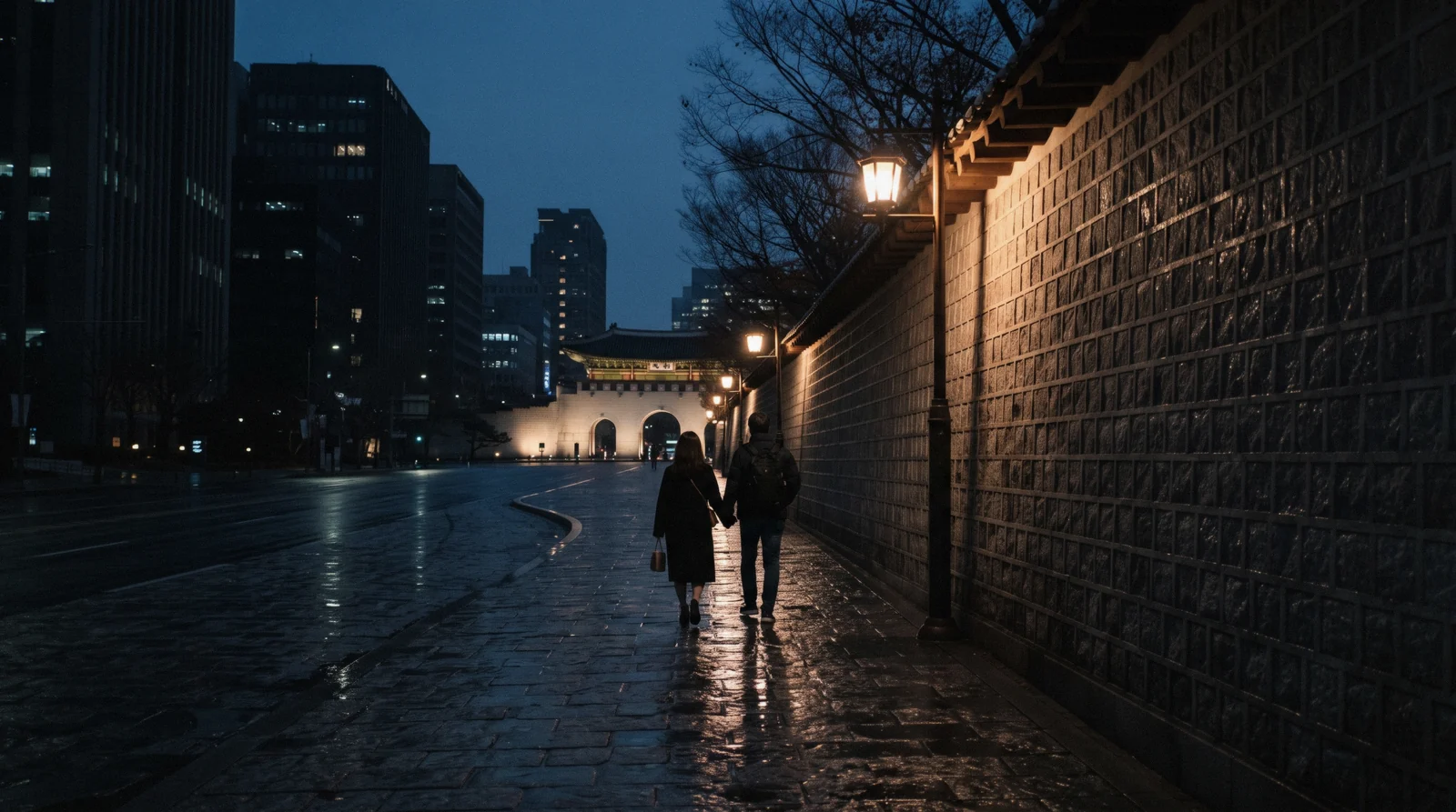 The lit palace wall along the Deoksugung stone-wall road with office towers behind, Seoul, South Korea
